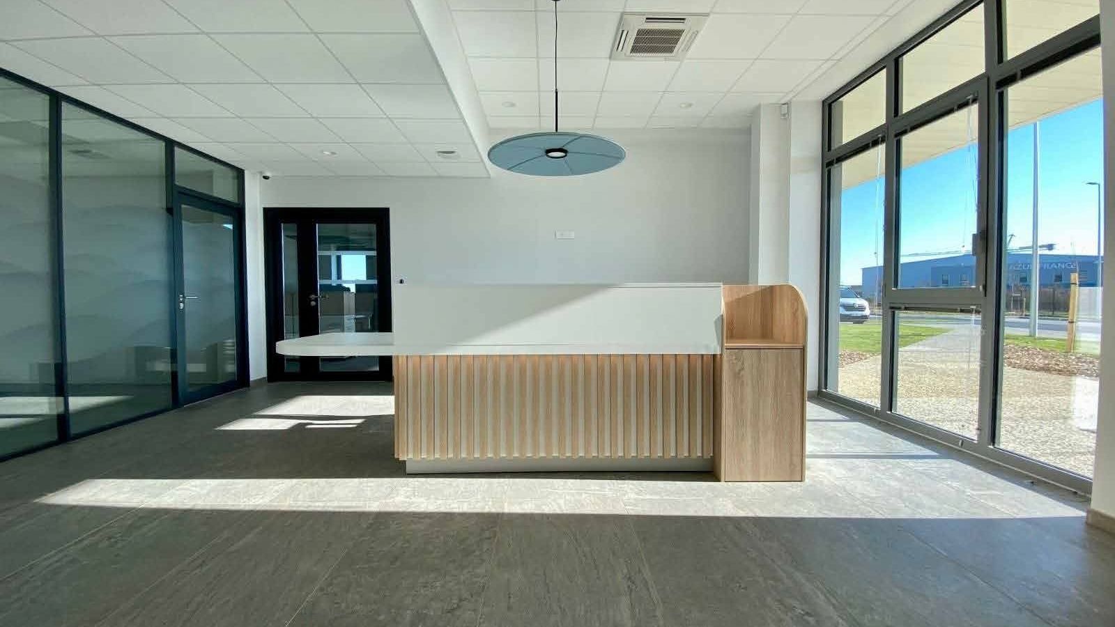 Espace de travail collaboratif avec plafond noir, grand mur sombre, chaises orange et comptoir en bois, aménagé par LIV Intérieur